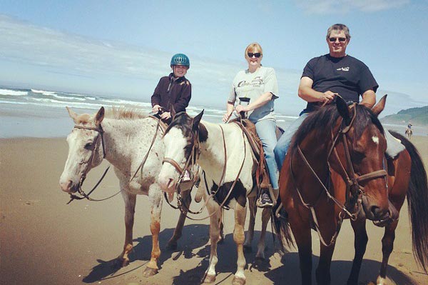Family horseback riding on the beach
